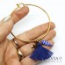 Bracciale bangle in acciaio color oro con ciondolo pesce e nappina